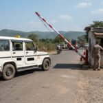 SUV taxi stopped at a state border checkpost with a barrier gate